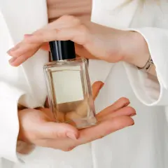 Hände halten eine Glasflasche mit Parfum.