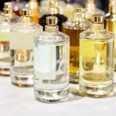 Mehrere Glasflaschen mit Parfüm in verschiedenen Farben und Größen, mit goldenen Verschlüssen.