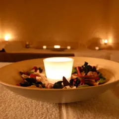 Eine leuchtende Kerze in einer Schale mit Potpourri auf einem Handtuch in einem Spa.