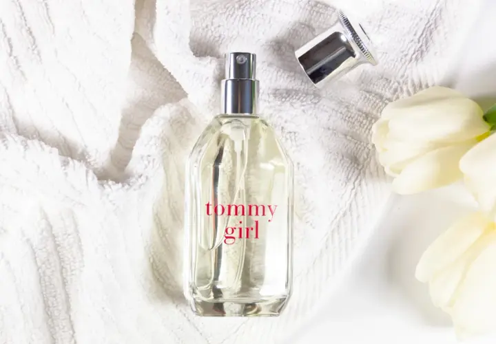 Tommy Girl Parfümflasche auf weißem Handtuch mit weißen Tulpen.