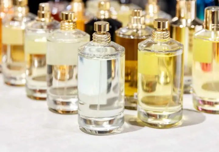 Mehrere Glasflaschen mit Parfüm in verschiedenen Farben und Größen, mit goldenen Verschlüssen.