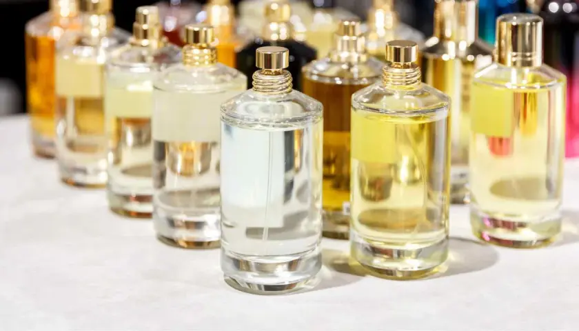 Mehrere Glasflaschen mit Parfüm in verschiedenen Farben und Größen, mit goldenen Verschlüssen.