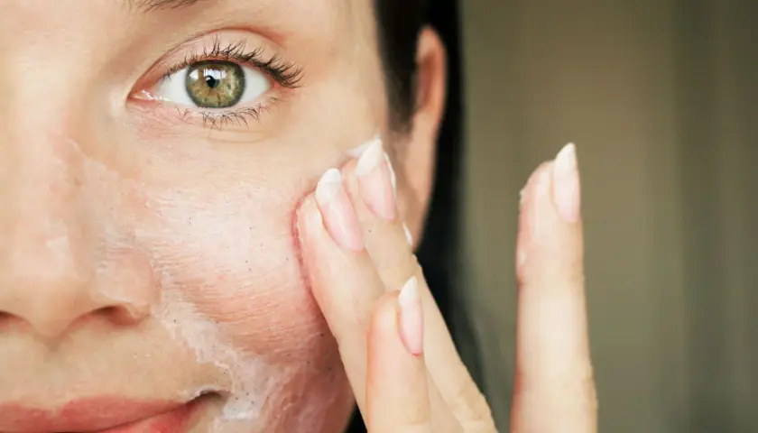 Nahaufnahme einer Frau, die sich eine Creme ins Gesicht aufträgt.