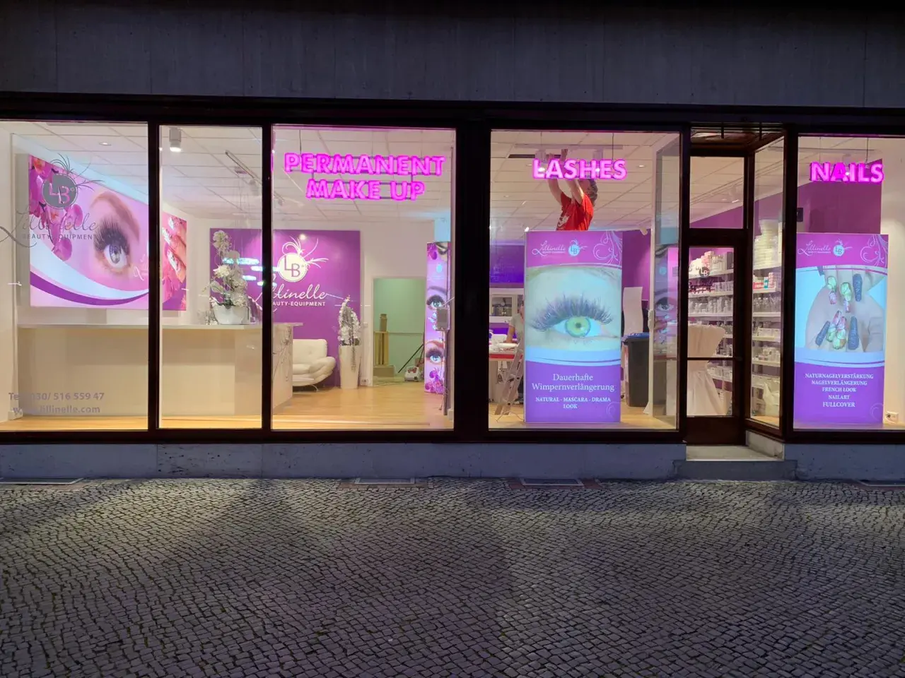 Kosmetikstudio mit Leuchtreklamen für Permanent Make-up, Lashes und Nails.
