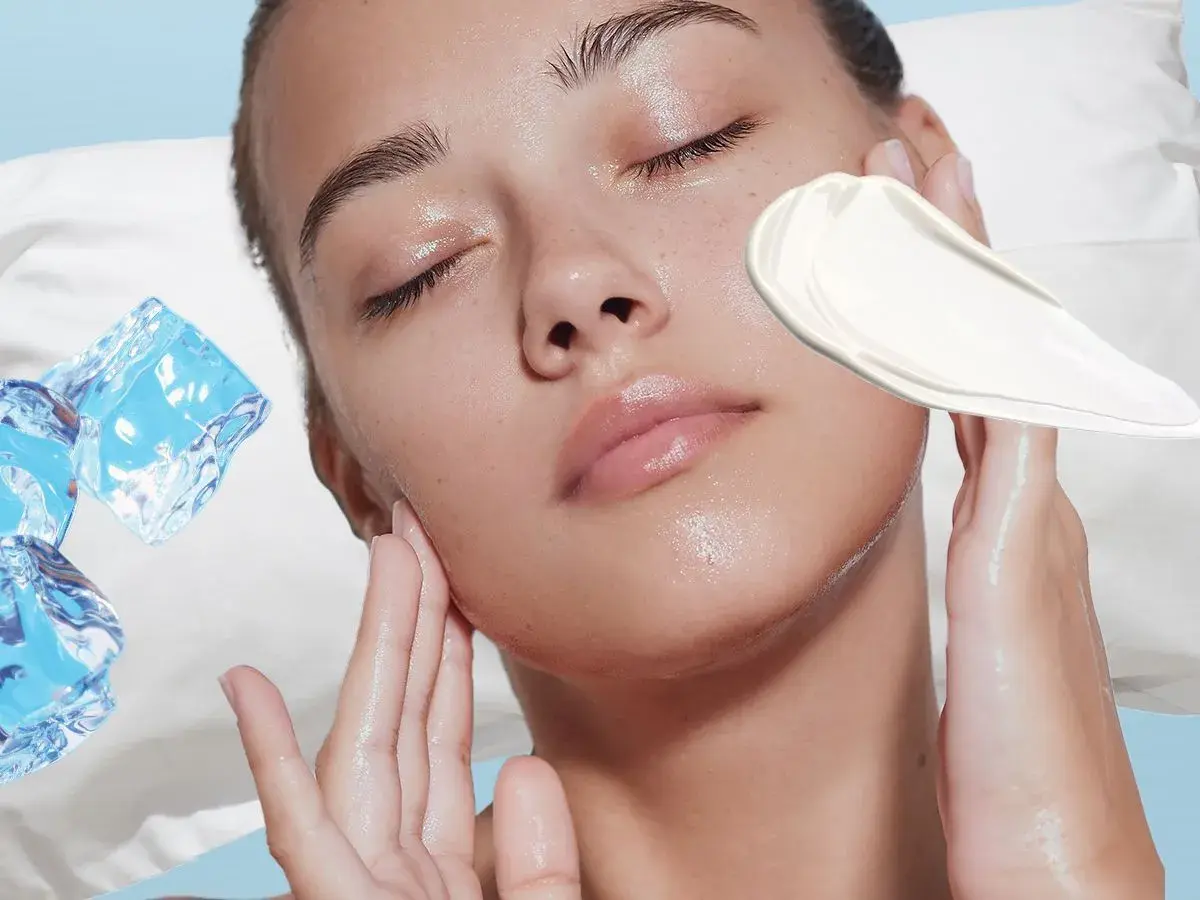 Frau mit geschlossenen Augen, Eiswürfel und Creme auf der Wange.
