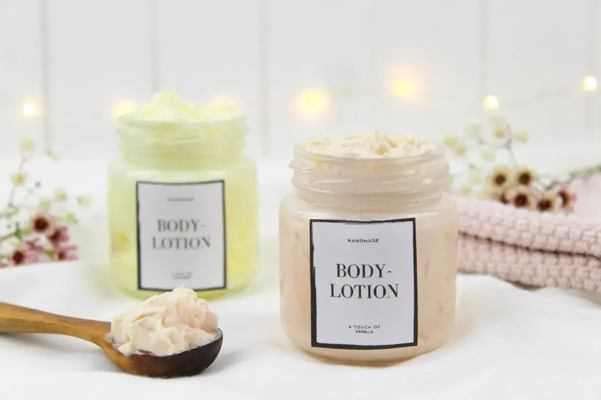 Zwei Gläser mit selbstgemachter Bodylotion, eine auf einem Holzlöffel.