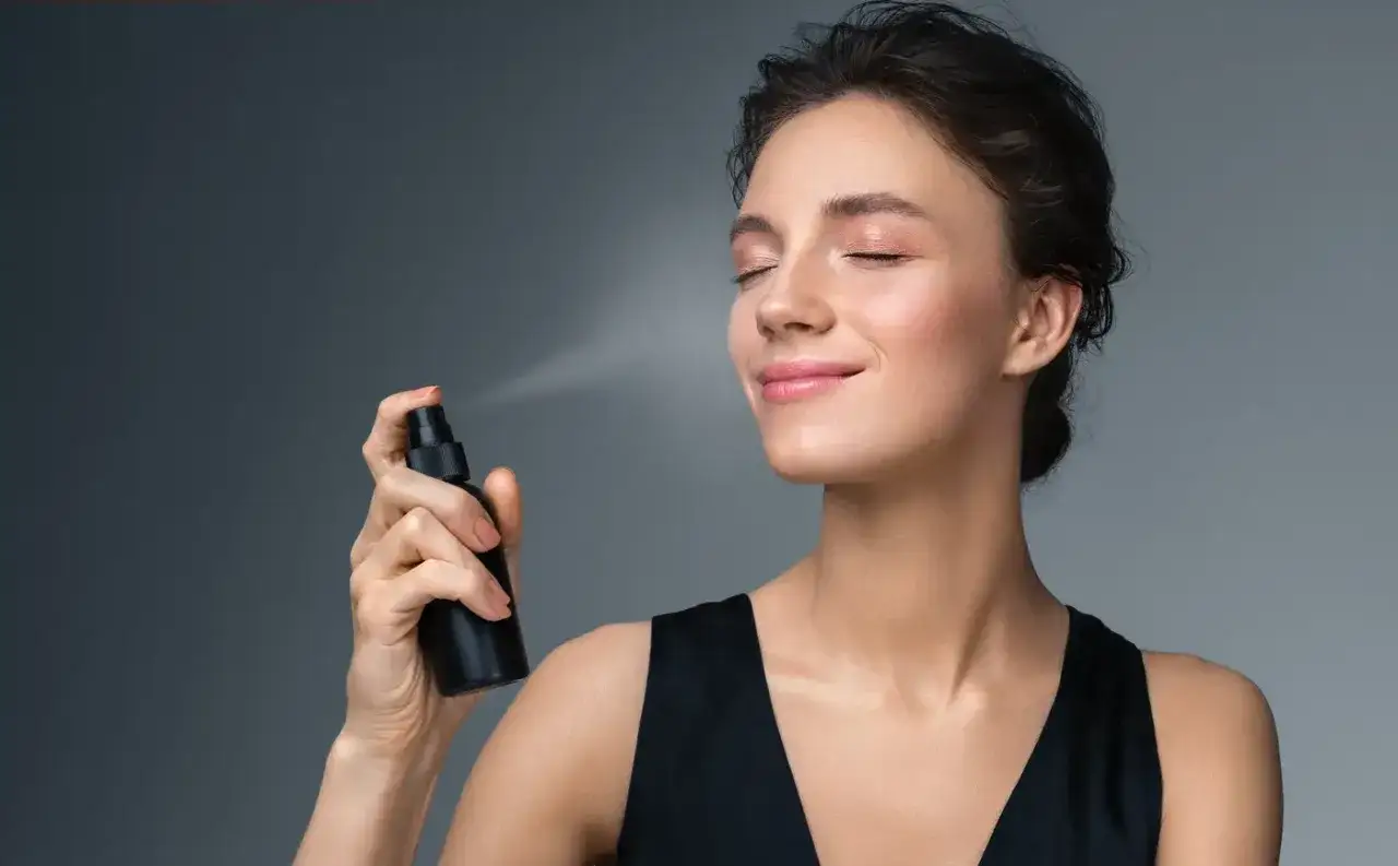 Frau spr&uuml;ht Setting Spray auf ihr Gesicht
